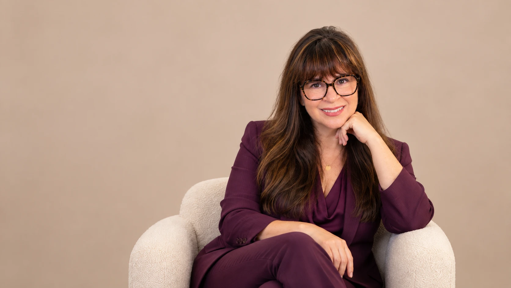 Dr. Alison Feit seated in an armchair, wearing a purple suit